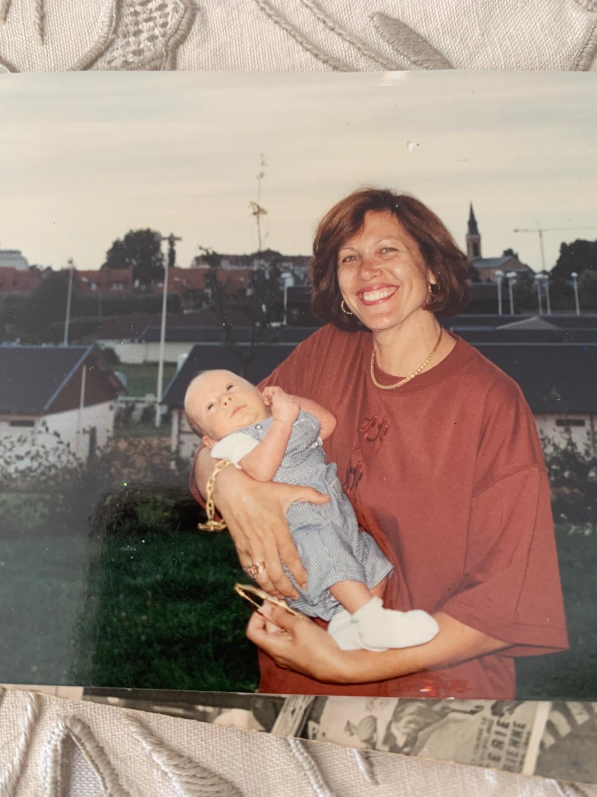Mamie Jeanine tenant Jordan Besnainou, **début août 1991, à Deauville**. Jordan a juste un mois. C'est dans l'appartement qu'avaient mon papa Angelo et ma grand-mère paternelle, au rez-de-chaussée avec un petit jardin. Le clocher derrière, c'est l'église de Deauville.